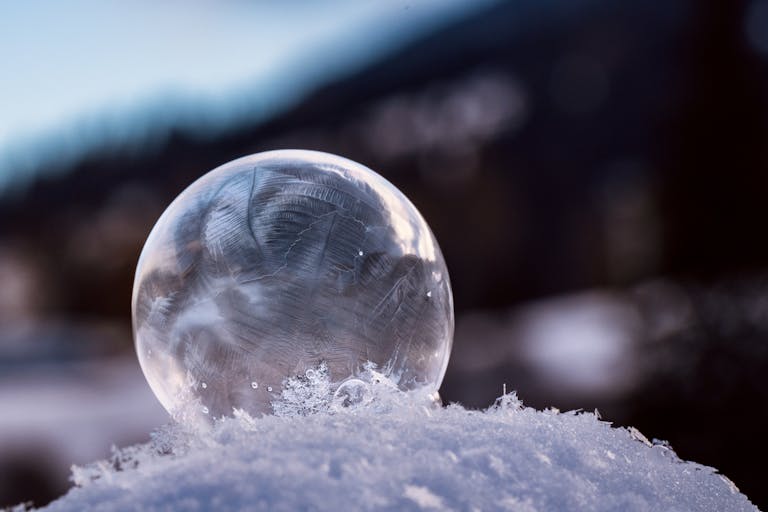 Captivating image of a delicate frozen bubble sitting on a snow surface, highlighting winter beauty.